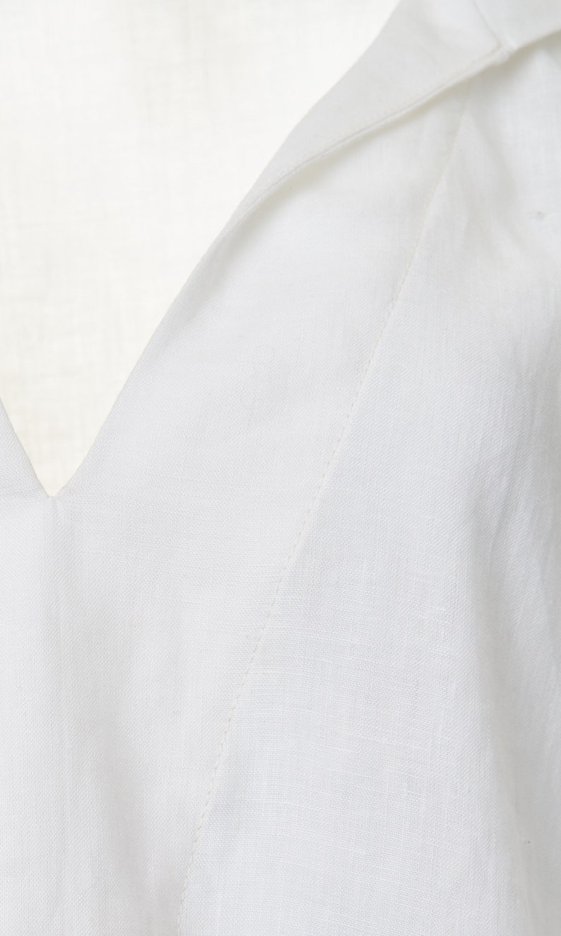 May include: Close-up of a white v-neck shirt with a stitched seam detail.