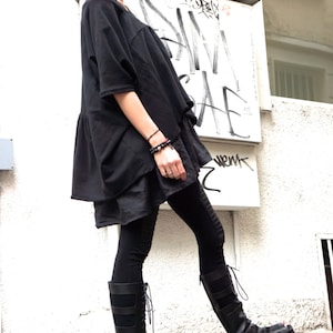 Puede incluir: Una mujer con una t&uacute;nica negra y leggings negros con sandalias de plataforma negras. Las sandalias tienen un dise&ntilde;o de cordones y una suela de plataforma gruesa.