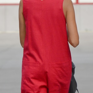 May include: A sleeveless red jumpsuit with a V-neckline and two pockets on the back.