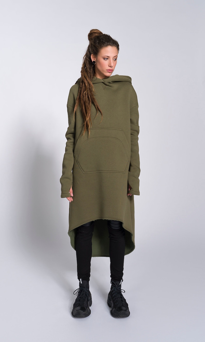May include: A long, olive green hooded sweatshirt with a large pocket on the front. The sweatshirt has a high-low hemline and is made of a soft, comfortable fabric.