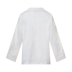 May include: A white long-sleeved shirt with a collared neckline. The shirt has a relaxed fit and a slightly cropped length.