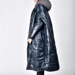 May include: A long, dark blue quilted puffer coat with a hood. The coat has a shiny, almost wet-look finish.