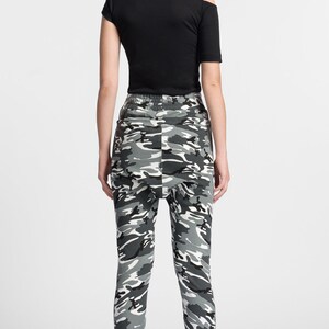 May include: A person wearing black and white camouflage pants with a black shirt and black and white sneakers.