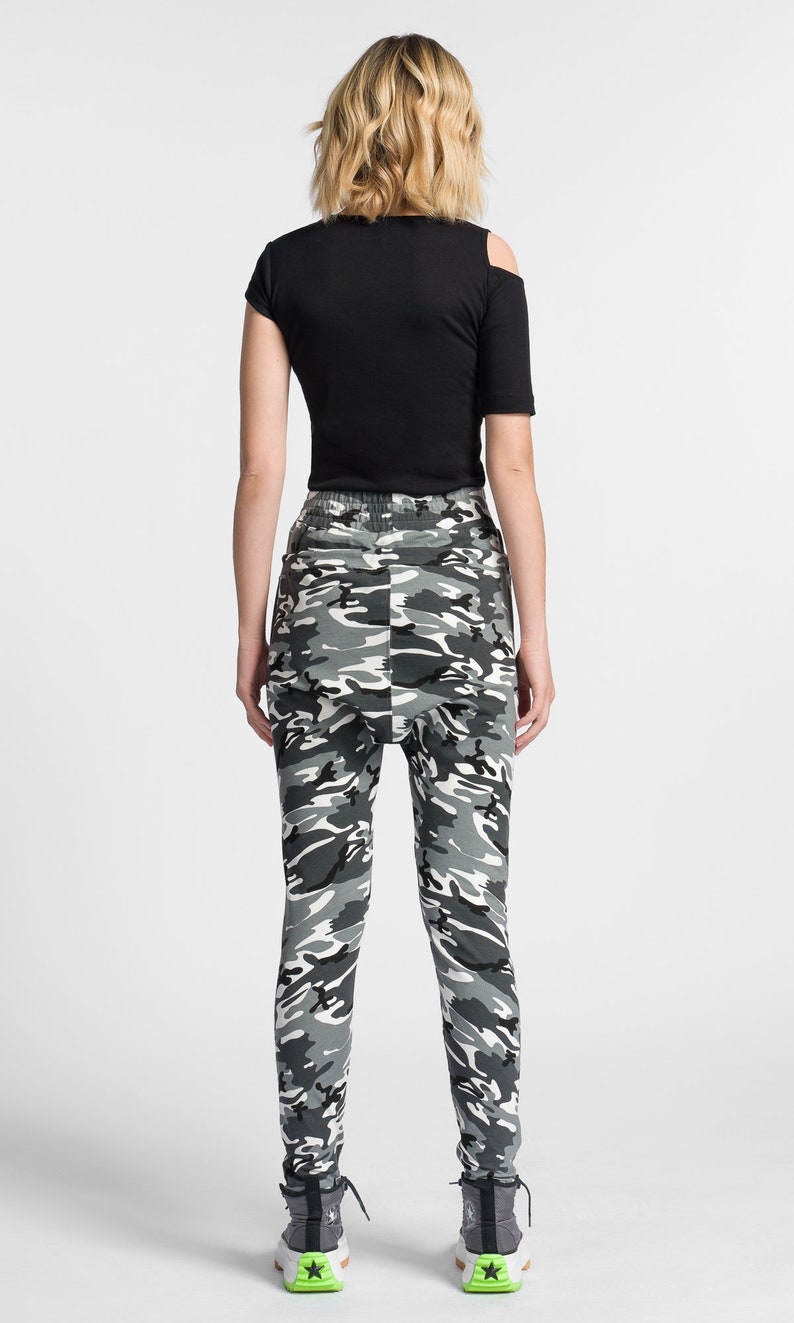 May include: A person wearing black and white camouflage pants with a black shirt and black and white sneakers.
