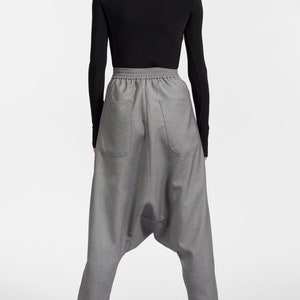 May include: Gray, loose-fitting pants with a drawstring waistband and a unique, gathered design at the knees. The pants are made of a textured fabric and have a relaxed fit.