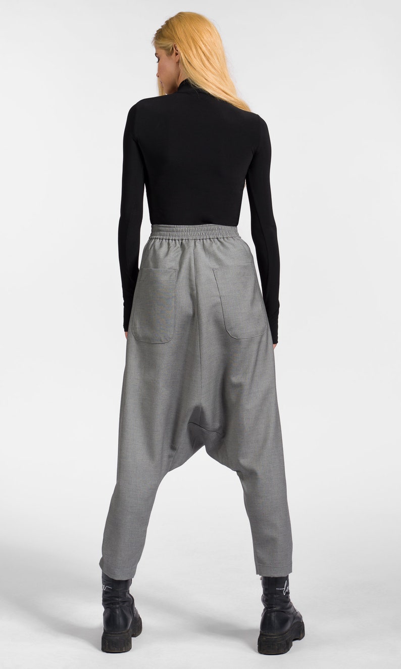 May include: Gray, loose-fitting pants with a drawstring waistband and a unique, gathered design at the knees. The pants are made of a textured fabric and have a relaxed fit.