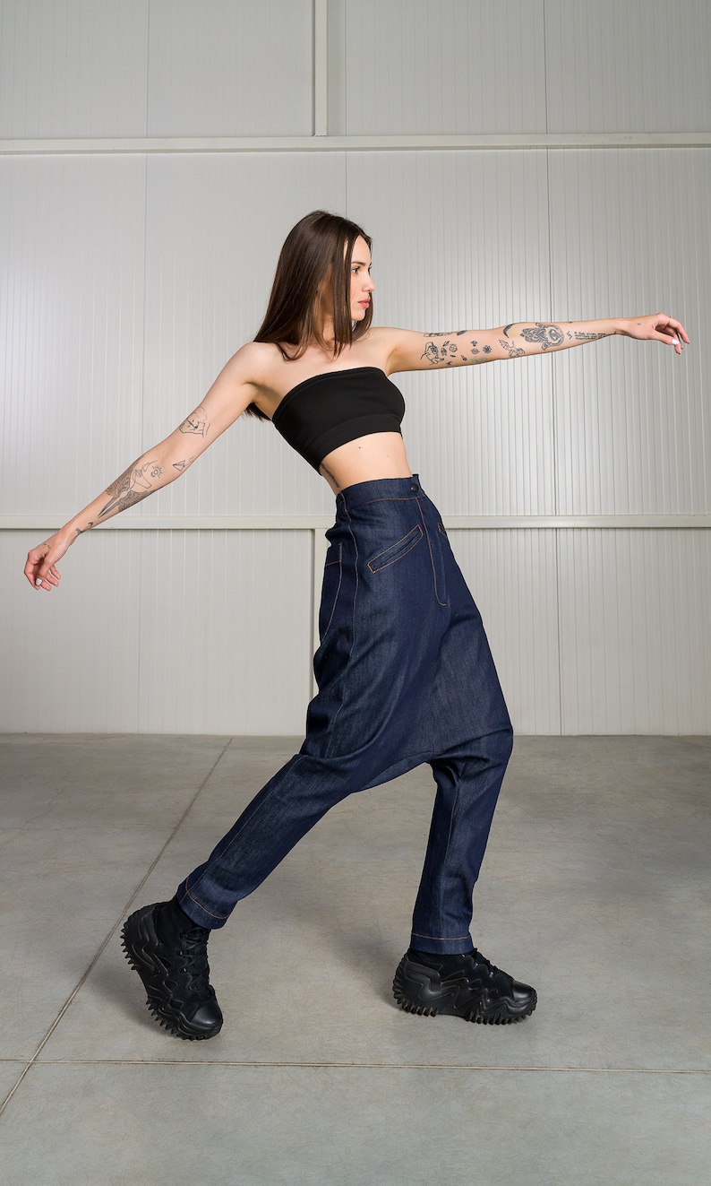 K&ouml;nnte beinhalten: Eine Frau tr&auml;gt ein schwarzes Bandeau-Top und eine dunkelblaue Jeanshose mit einem einzigartigen, weiten Stil. Sie tr&auml;gt schwarze Sneaker mit einer dicken Sohle.