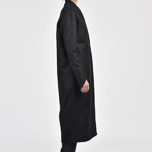 May include: A long black coat with a shawl collar and a long, flowing silhouette. The coat is made of a soft, luxurious fabric and has a relaxed fit.
