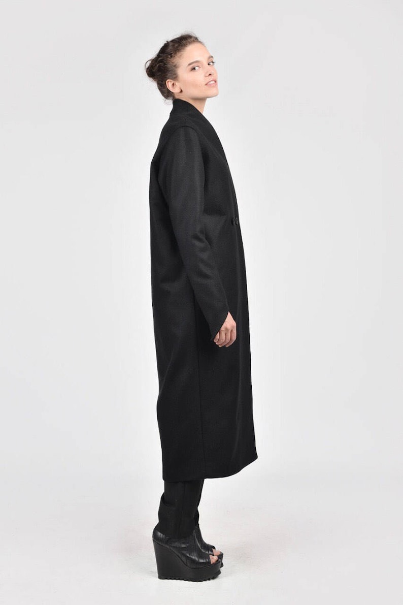 May include: A long black coat with a shawl collar and a long, flowing silhouette. The coat is made of a soft, luxurious fabric and has a relaxed fit.