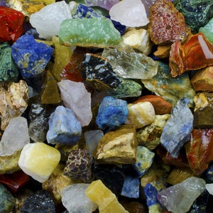 May include: A collection of colorful, natural, and polished gemstone chips. The chips are various shapes and sizes, including green, blue, red, purple, and brown.