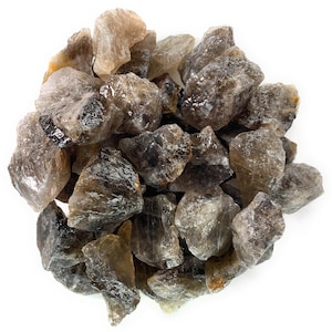 Puede incluir: Un montón de cristales de cuarzo ahumado, con una variedad de formas y tamaños. Los cristales son de color marrón claro con una apariencia translúcida.