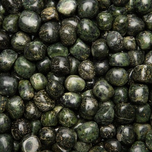 May include: A close-up of a collection of dark green tumbled stones with black and white flecks. The stones are smooth and polished, and they are arranged in a random pattern.
