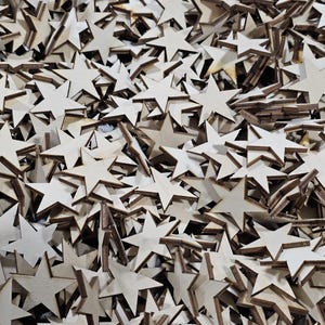 Puede incluir: Un mont&oacute;n de estrellas de madera sin terminar. Las estrellas son de color claro con un contorno marr&oacute;n m&aacute;s oscuro y var&iacute;an en tama&ntilde;o. Algunas est&aacute;n apiladas, creando una superficie texturizada. Ideal para manualidades y proyectos de bricolaje.