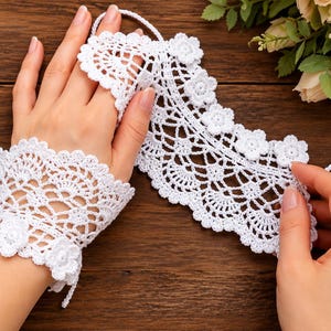 May include: A white crochet lace fingerless glove featuring an intricate openwork pattern and a scalloped edge adorned with small floral motifs. The design includes a loop for the middle finger and a matching separate lace piece.