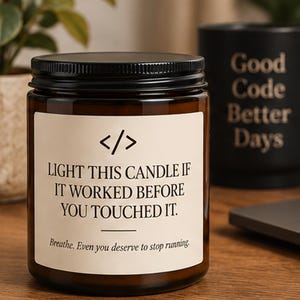 Può includere: Una candela in un barattolo di vetro marrone con coperchio nero e un'etichetta bianca con il testo </>, LIGHT THIS CANDLE IF IT WORKED BEFORE YOU TOUCHED IT. Breathe. Even you deserve to stop running. L'etichetta è centrata sul barattolo.