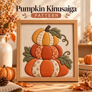 May include: A framed Kinusaiga fabric art piece featuring a stack of three pumpkins in shades of orange, yellow, and white with floral and gingham patterns. The artwork includes green fabric leaves and vines, all set within a light wood frame.