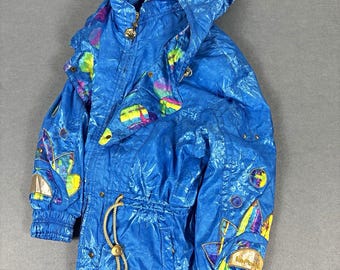 May include: A bright blue hooded jacket featuring a shiny, crinkled texture and a drawstring waist. The jacket is decorated with colorful, abstract geometric patches in shades of yellow, purple, and green on the sleeves and collar area.