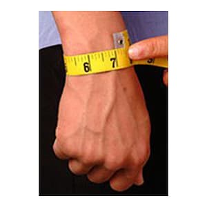 May include: A person's wrist is being measured with a yellow measuring tape. The tape shows a measurement of approximately 6.5 inches. The person's hand is visible, with the tape wrapped around the wrist.