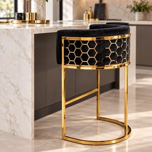 Puede incluir: Un taburete de bar con asiento tapizado en terciopelo negro y respaldo curvo. El respaldo está revestido con un marco de metal dorado pulido con un patrón geométrico de panal. El taburete tiene una base de metal dorado con soporte semicircular.