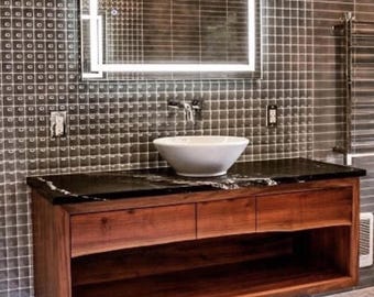 May include: A floating bathroom vanity with a dark countertop and three drawers. The vanity is made of wood and has a shelf underneath. A white porcelain sink sits on the countertop.