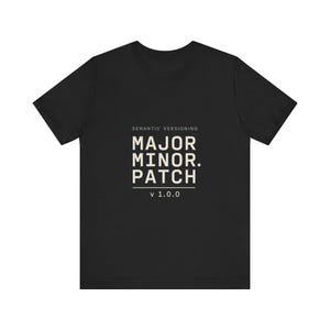 以下が含まれることがあります： 中央にSEMANTIC VERSIONING、MAJOR. MINOR. PATCH、v 1.0.0というテキストがライトベージュ色でプリントされた、黒の半袖Tシャツ。デザインは水平線を用いたブロック形式で配置されています。