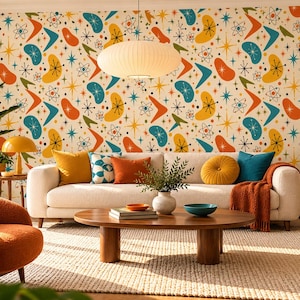 May include: Wallpaper featuring a repeating pattern of colorful mid-century modern shapes including boomerangs, starbursts, and atomic symbols in shades of orange, yellow, and teal on a cream background, covering a large interior wall.
