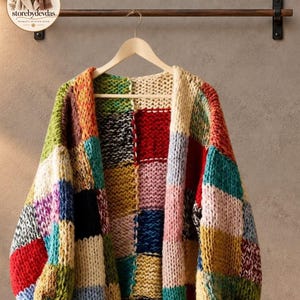 Pode incluir: Um cardigã de malha grossa com um design de retalhos, apresentando grandes quadrados em várias cores, incluindo vermelho, amarelo, azul, verde, rosa e creme. A peça tem mangas compridas, frente aberta e uma estrutura de fio espesso.