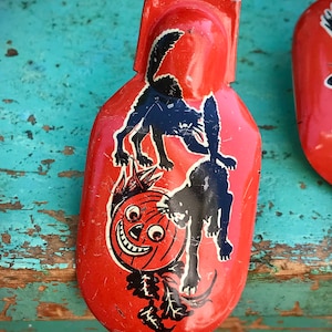 May include: Red metal Halloween noisemaker with a black and white illustration of two black cats and a jack-o-lantern.
