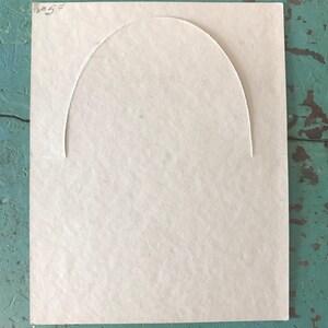 May include: A blank, off-white card with a semi-circular cut-out in the center. The card has the number "854" written in black ink in the top right corner.