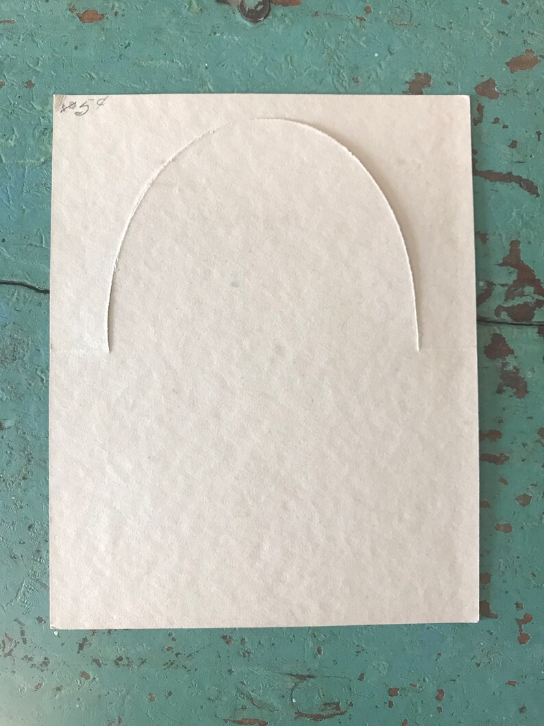 May include: A blank, off-white card with a semi-circular cut-out in the center. The card has the number "854" written in black ink in the top right corner.