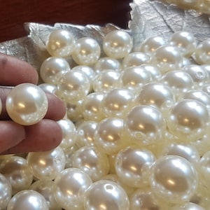 Peut inclure: Un grand bol rempli de perles blanches. Les perles sont lisses et brillantes, et elles sont toutes de la même taille.