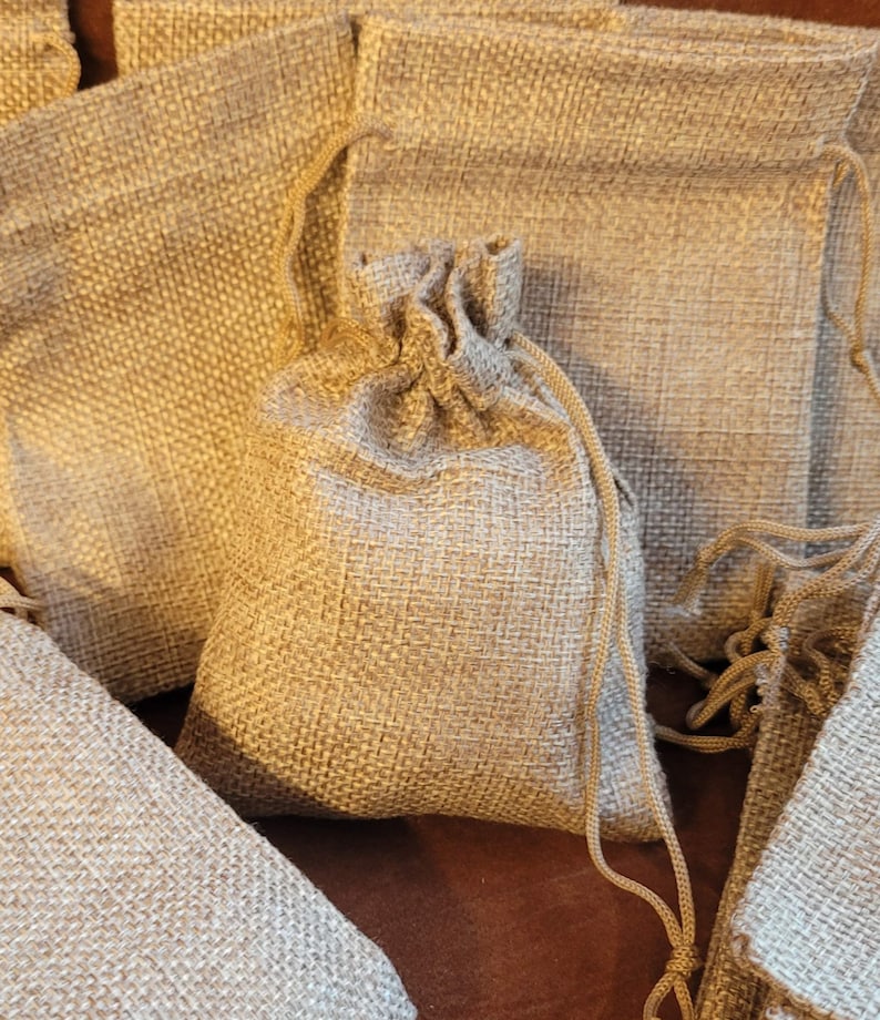 May include: A group of small, brown burlap drawstring bags. The bags are made of a natural, woven fabric and have a rustic, earthy look.