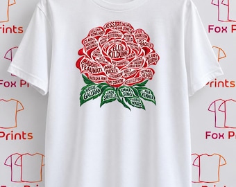 May include: A white short-sleeved t-shirt featuring a large graphic of a red rose made of names. The center of the rose displays the name Ellie Kildunne, surrounded by various other names in red and green text, with green leaves at the base.