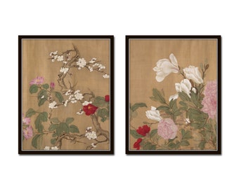 May include: Two framed paintings with floral motifs. The left painting features a branch of white blossoms with pink and red flowers. The right painting features a branch of white magnolia blossoms with pink and red flowers.