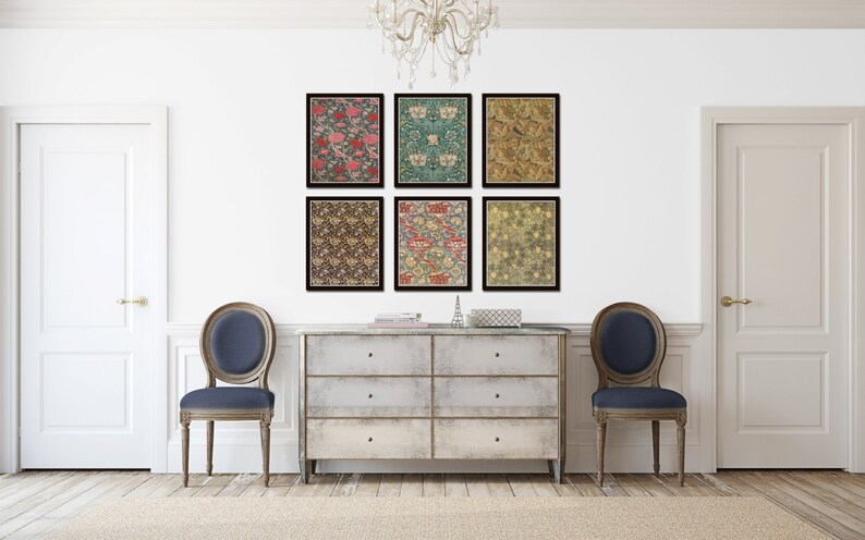 May include: Six framed prints of floral patterns in various colors, including red, green, and gold, are displayed on a white wall above a light-colored dresser with six drawers. Two blue chairs are placed on either side of the dresser.