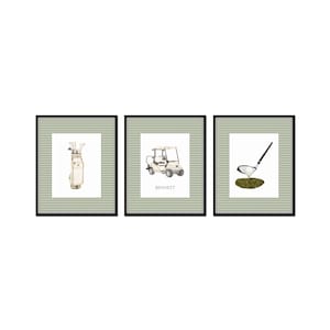 May include: Three framed prints with a green and white checkered background. The prints feature a golf bag with clubs, a golf cart, and a golf club with a ball on the green.