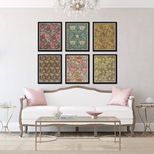 May include: Six framed prints of floral patterns in various colors, including pink, green, blue, and brown, are displayed on a white wall above a white couch with pink throw pillows. Two gold side tables with decorative objects are on either side of the couch.