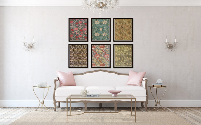 May include: Six framed prints of floral patterns in various colors, including pink, green, blue, and brown, are displayed on a white wall above a white couch with pink throw pillows. Two gold side tables with decorative objects are on either side of the couch.