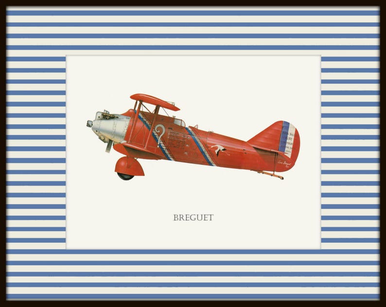 May include: A framed print featuring a vintage red biplane with blue and white accents. The biplane has a silver propeller and the word "BREGUET" is printed below the plane. The frame has a navy blue border with white and blue stripes.