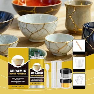 Könnte beinhalten: Ein Keramik-Reparaturset mit einer gelb-schwarzen Schachtel und Flasche, beschriftet mit Ceramic Repair Adhesive 50ml. Das Set enthält einen weißen Spatel, eine Mischschale, zwei kleine Dosen mit Gold- und Silberpulver, einen Holzstab, einen Becher und einen Handschuh.