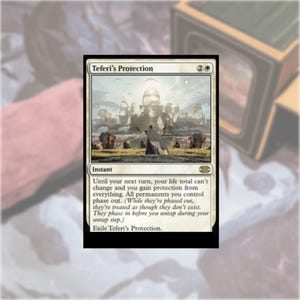 May include: A rectangular Magic: The Gathering trading card titled Teferi's Protection. The card features an illustration of a figure standing before a large, glowing city with elephants in the foreground. The text explains the instant spell effect.
