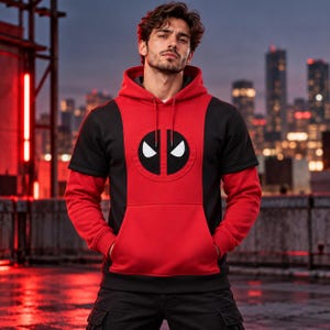 Pode incluir: Uma camisola com capuz vermelha e preta com um logótipo central do Deadpool no peito. A peça tem um capuz vermelho com cordões, mangas compridas vermelhas e um design de painéis pretos nos ombros e lados, incluindo um bolso frontal canguru.
