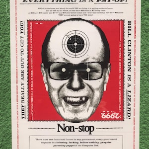 Può includere: Un poster con un design rosso e bianco con il ritratto di un uomo con gli occhiali e un bersaglio sopra la testa. Il testo include "Everything is a Psy-Op!" e "Bill Clinton is a Lizard!". Il poster ha varie altre frasi e il numero "666".
