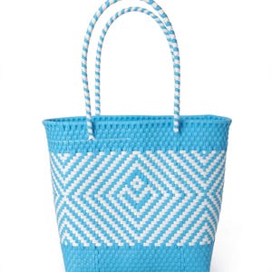 May include: A bright blue and white woven tote bag featuring a geometric diamond pattern across the centre. The bag has two matching blue and white braided handles attached to the top rim, with a solid blue base and a solid blue top border.