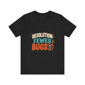 May include: A black short-sleeved t-shirt featuring a graphic print with the text "RESOLUTION: FEWER BUGS" in cream, teal, and orange. The design includes a small illustration of a bug inside a red prohibition circle and a firework icon.