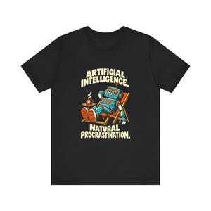 May include: A black t-shirt featuring a graphic of a blue robot lounging in a beach chair with a coffee mug on a side table. The text above reads ARTIFICIAL INTELLIGENCE and the text below reads NATURAL PROCRASTINATION in a cream-coloured font.