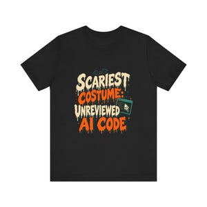 May include: A black short-sleeved t-shirt featuring a graphic with a bat and a computer window icon containing a skull. The text reads SCARIEST COSTUME: UNREVIEWED AI CODE in a dripping, orange and cream-coloured font against the black fabric.