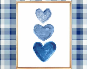 May include: Three watercolor hearts in shades of blue, arranged vertically in a wooden frame against a blue and white plaid background.