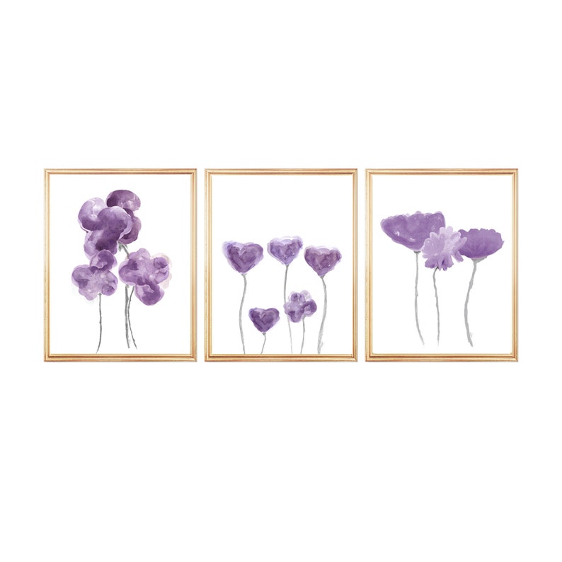Pu&ograve; includere: Set di tre stampe ad acquerello incorniciate con fiori astratti viola su sfondo bianco.