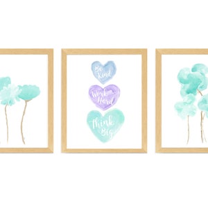 May include: Three framed watercolor prints with inspirational messages. The center print features three stacked hearts with the words "Be Kind", "Work Hard", and "Think Big". The left print features two light blue watercolor flowers. The right print features three light blue watercolor flowers.